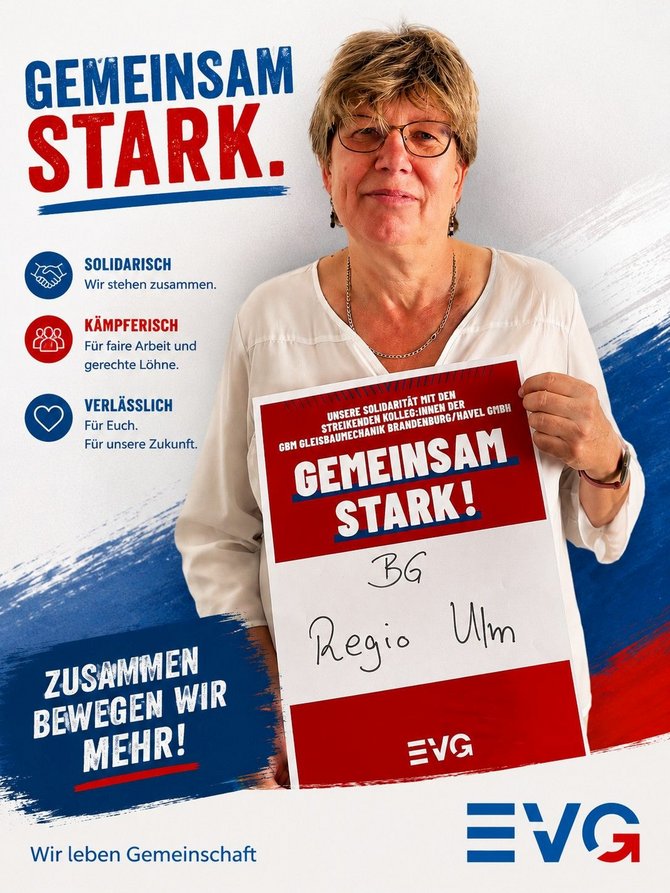 Person mit Brille und hellem Oberteil steht vor einem EVG‑Banner und hält ein Schild in der Hand. Auf dem Banner steht links groß „GEMEINSAM STARK.“ sowie darunter: „SOLIDARISCH – Wir stehen zusammen.“, „KÄMPFERISCH – Für faire Arbeit und gerechte Löhne.“, „VERLÄSSLICH – Für Euch. Für unsere Zukunft.“ Unten links steht „ZUSAMMEN BEWEGEN WIR MEHR!“ und darunter „Wir leben Gemeinschaft“. Auf dem gehaltenen Schild steht: „UNSERE SOLIDARITÄT MIT DEN STREIKENDEN KOLLEG:INNEN DER GBM GLEISBAUMECHANIK BRANDENBURG/HAVEL GMBH“, darunter groß „GEMEINSAM STARK!“, handschriftlich „BG Regio Ulm“ sowie unten das EVG‑Logo. Rechts unten auf dem Banner befindet sich ebenfalls ein EVG‑Logo.