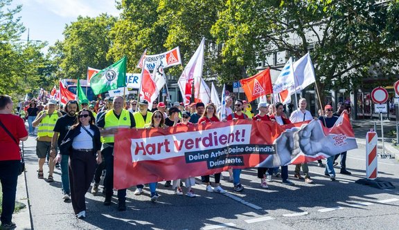 Demonstrationszug in einer Innenstadtstraße. Mehrere Personen tragen Fahnen und ein großes Banner mit der Aufschrift „ZUKUNFT BRAUCHT JUGEND!“. Sichtbare Schilder enthalten unter anderem die Texte „RENTE mit 67 ist kein Princess Treatment!“ und „Mein Gehalt kann nicht mal mehr GIRLMATH schön reden!“. Sichtbare Fahnen tragen unter anderem die Aufschriften „Gemeinsam stark.“ und „EVG JUGEND“.