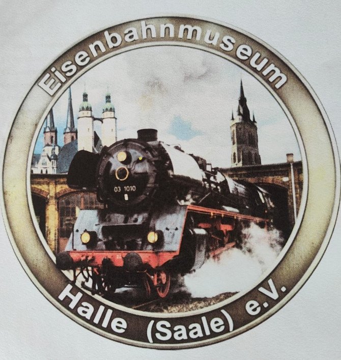 Rundes Logo mit der Aufschrift „Eisenbahnmuseum Halle (Saale) e.V.“. In der Mitte ist ein Foto einer historischen Dampflokomotive (Nummer 03 1010) zu sehen, die Dampf ausstößt. Im Hintergrund des Bildes erkennt man eine Brücke sowie markante Kirchtürme der Stadt Halle.