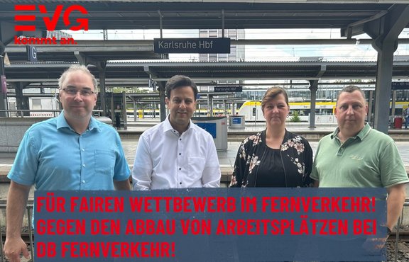 Werbegrafik an einem Bahnhof mit dem Schild „Karlsruhe Hbf“. Vier Personen stehen auf einem Bahnsteig vor Gleisen und überdachten Bahnsteigen. Oben links befindet sich das rote EVG-Logo mit dem Text „kommt an.“. Im unteren Bildbereich steht auf einem blauen Balken in roter Schrift: „FÜR FAIREN WETTBEWERB IM FERNVERKEHR! GEGEN DEN ABBAU VON ARBEITSPLÄTZEN BEI DB FERNVERKEHR!“. Im Hintergrund sind weitere Bahnsteige, Beschilderungen und ein Zug zu sehen.