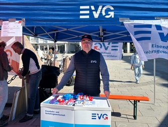 Ein einzelner Infotisch steht unter einem blauen Zelt mit großer weißer Aufschrift „EVG“ auf der Zeltkante. Der Stand befindet sich ebenfalls im öffentlichen Raum.